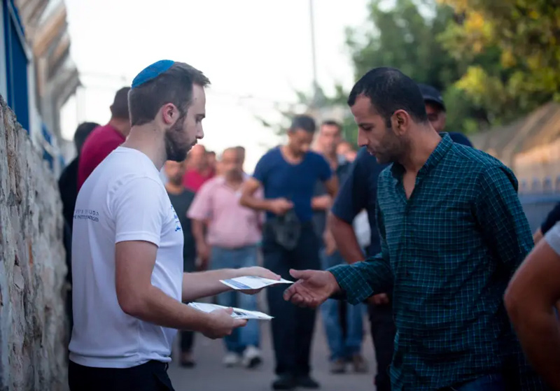 A representative for Blue & White Human Rights offering pamphlets to Palestinians