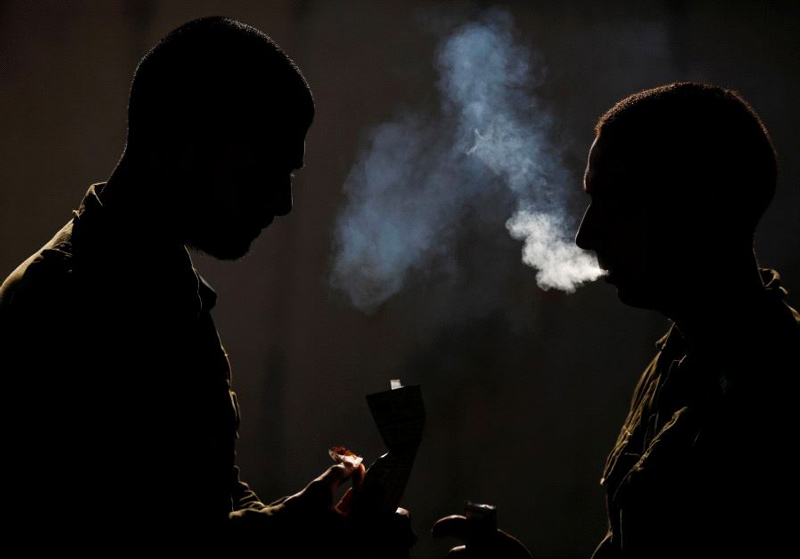 Silhouetted Israeli soldiers from the Home Front Command Unit take a smoking break during an urban warfare drill inside a mock village at Tze'elim army base in Israel's Negev Desert.