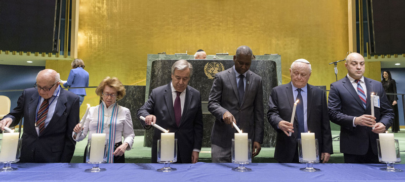 A candle lighting ceremony takes place at the United Nations Holocaust Memorial Ceremony ’75 years after Auschwitz – Holocaust Education and Remembrance for Global Justice’ on the occasion of the International Day of Commemoration in Memory of the Victims of the Holocaust. Lighting the candles are, from left to right: Theodor Meron, former President of the UN International Residual Mechanism for Criminal Tribunals; Irene Shashar, Holocaust survivor; Secretary-General António Guterres; Tijjani Muhammad-Bande, President of the seventy-fourth session of the United Nations General Assembly; Shraga Milstein, Holocaust survivor; and Dan Pavel Doghi, Chief of the Contact Point for Roma and Sinti Issuesof the Office for Democractic Institutions and Human Rights of the Organization for Security and Co-operation in Europe.