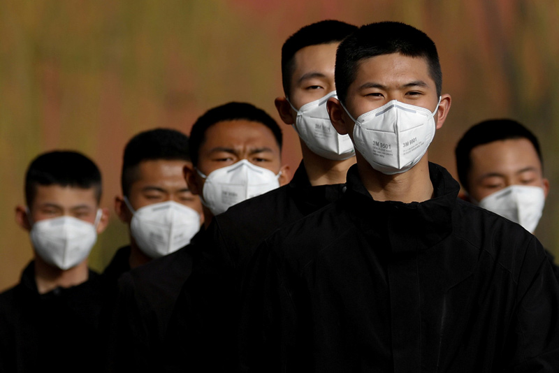 Security personnel wearing face masks to contain the spread of coronavirus disease (COVID-19) walk along a street outside Forbidden City in Beijing, China March 18, 2020.