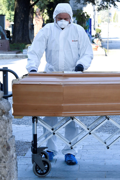 Men in protective masks transport a coffin of a person who died from coronavirus disease (COVID-19), into a cemetery in Bergamo, Italy March 16, 2020.