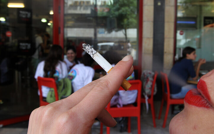 A woman smoking a cigarette outside an Israeli cafe.