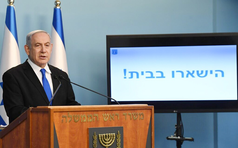Prime Minister Benjamin Netanyahu at a press conference on the coronavirus, March 17, 2020. The text on the screen reads: “Stay home!”