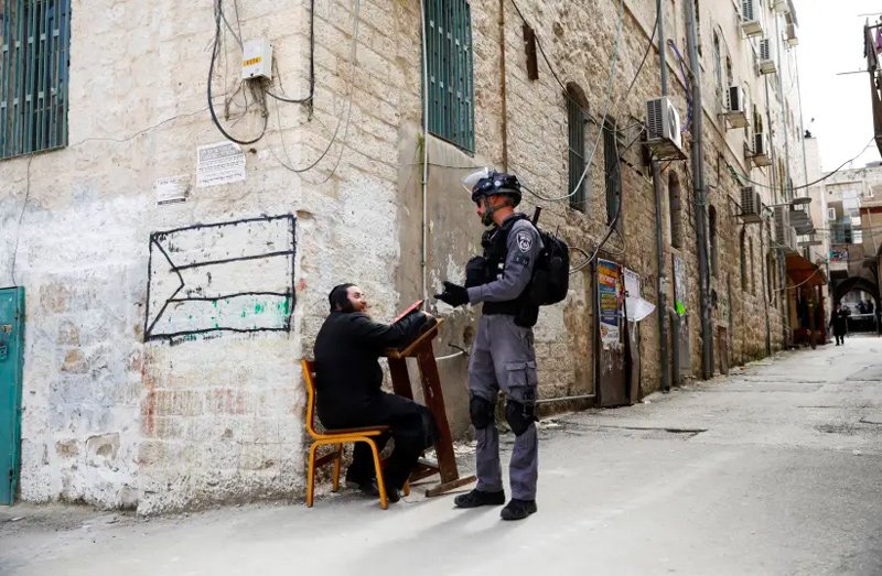 An ultra-Orthodox Jewish man speaks to an Israeli policeman after police removed him from a synagogue before closing it as they enforce restrictions of a partial lockdown against the coronavirus disease (COVID-19) in Mea Shearim neighbourhood of Jerusalem March 30, 2020.