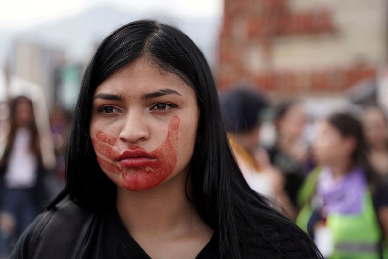 A woman, with a red hand marked on her face to denounce gender violence, takes part in a march to mark International Women's Day in Bogota, Colombia, March 8, 2020.