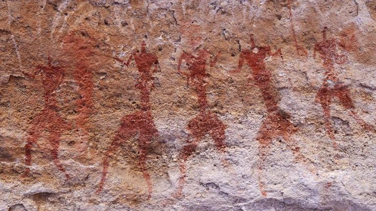 Neolithic rock paintings of dancing people at the Tassili n 'Ajjer National Park in Algeria.