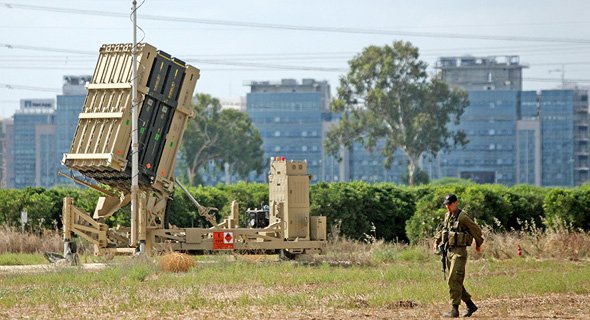 An Israeli soldier protects an Iron Dome battery.