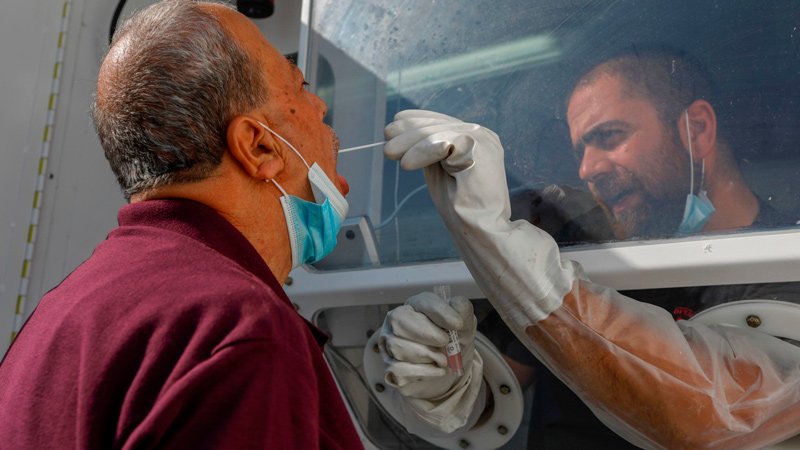 A paramedic from the Magen David Adom, Israel's version of the Red Cross, samples a Palestinian man for coronavirus at a mobile testing station in east Jerusalem on July 5.