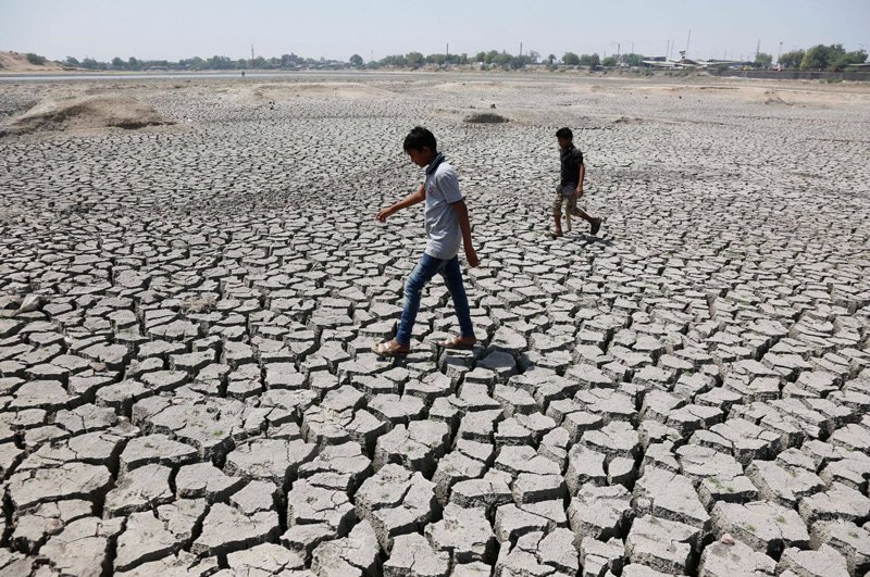 In this May 14, 2016, file photo, boys on their way to play cricket walk through a dried patch of Chandola Lake in Ahmadabad, India. The decade that just ended was by far the hottest ever measured on Earth, capped off by the second-warmest year on record, NASA and the National Oceanic and Atmospheric Administration reported Wednesday, Jan. 15, 2020.