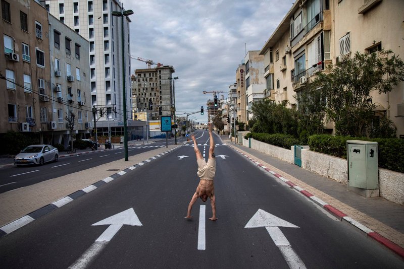 An Israeli man stands on his hands on an empty road during a lockdown following government measures to help stop the spread of the coronavirus, in Tel Aviv, April 8, 2020.