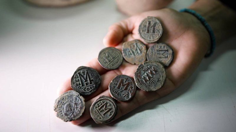 An archaeologist holds bronze coins from the Byzantine period during a media tour at Israel's National Treasures Storeroom, Beit Shemesh, March 19, 2017.