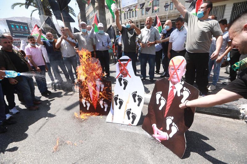 Palestinian protesters burning pictures of Prime Minister Benjamin Netanyahu, Abu Dhabi Crown Prince Sheikh Mohammed bin Zayed Al-Nahyan, and US President Donald Trump.