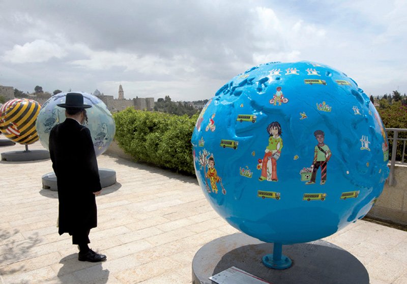 An ultra-Orthodox man observes the giant globes displayed outside the walls of Jerusalem’s Old City; the initiative of the non-profit organization Cool Globes aims to raise awareness of climate change.