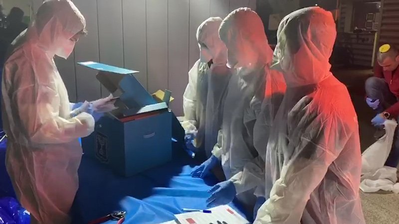 Elections officials in protective gear count ballots from people in coronavirus quarantine for the March 2020 election.