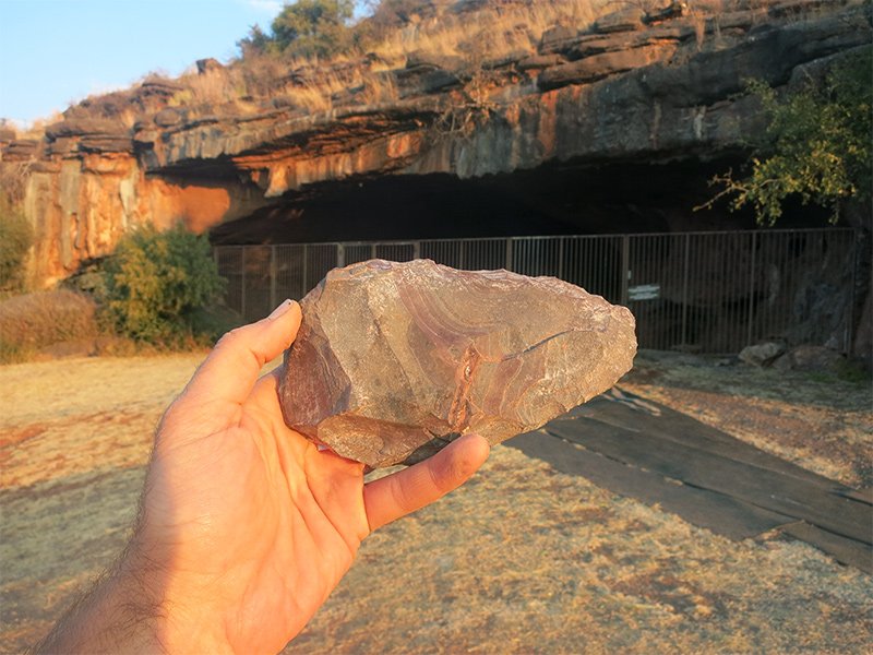 A handaxe from the Achelean layers at Wonderwerk. In the background is the cave entrance.