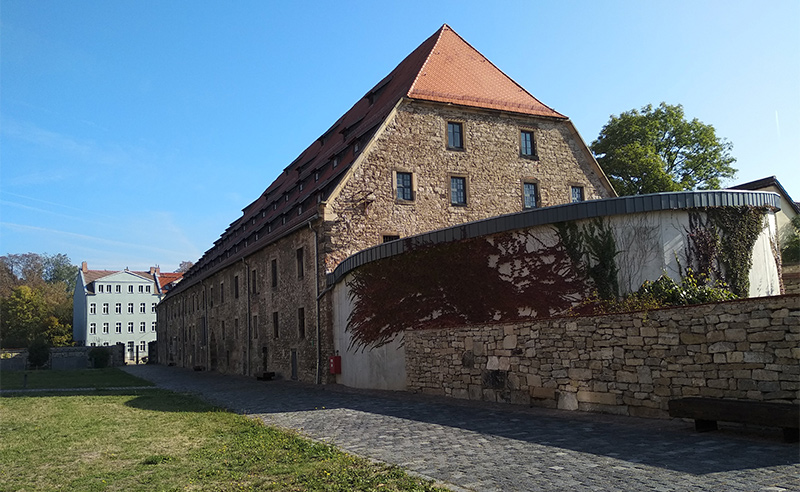 While converting the 15th-century granary (large brown building) into a parking garage in Erfurt, Germany, graves from the Jewish cemetery underneath were uncovered. After a rescue excavation to move the remains to a 19th-century Jewish cemetery nearby, an access ramp was put in place (circular structure on the right).
